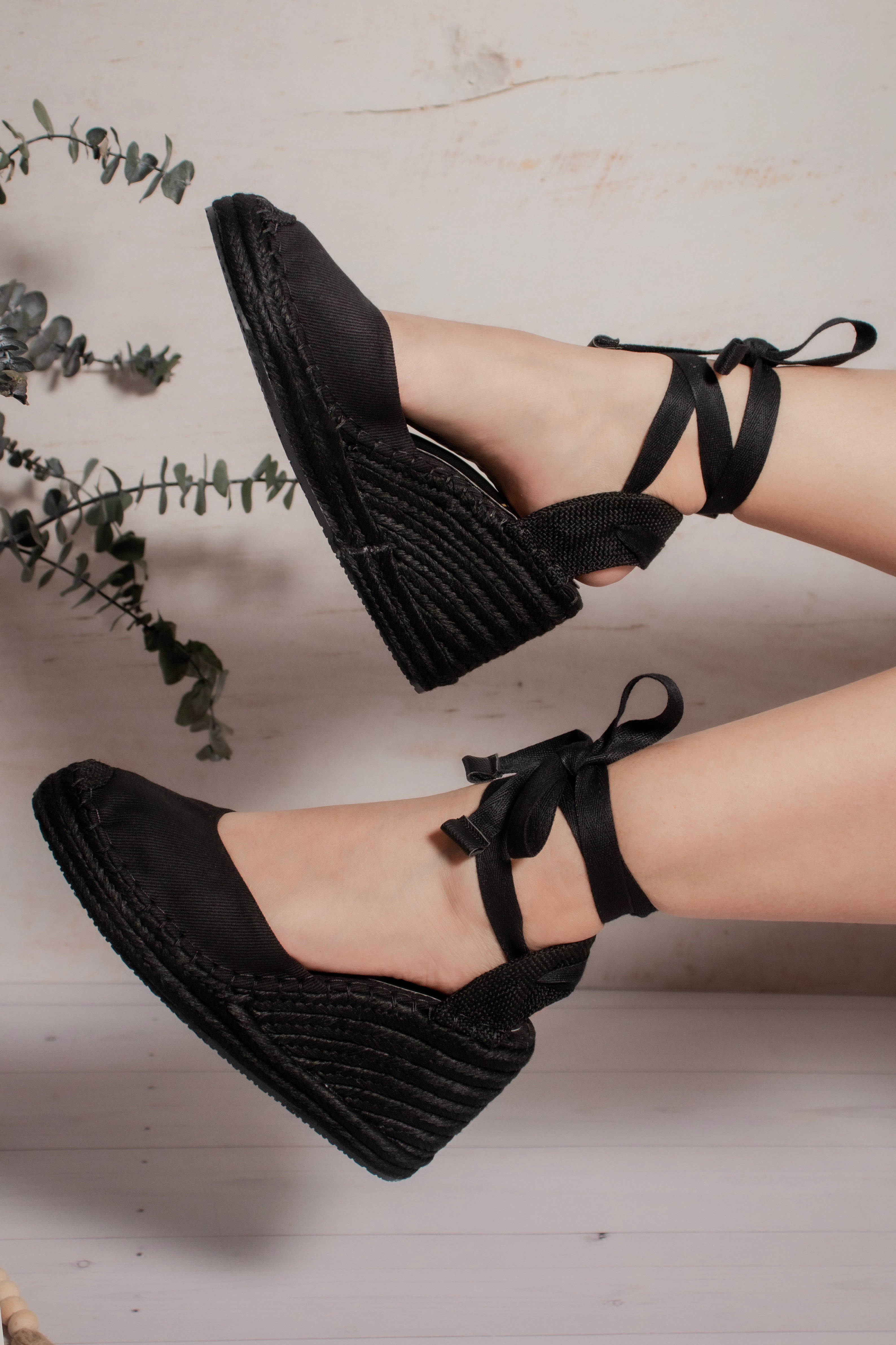 Vista lateral de las espadrilles de plataforma Myriam color negro con amarre al tobillo.